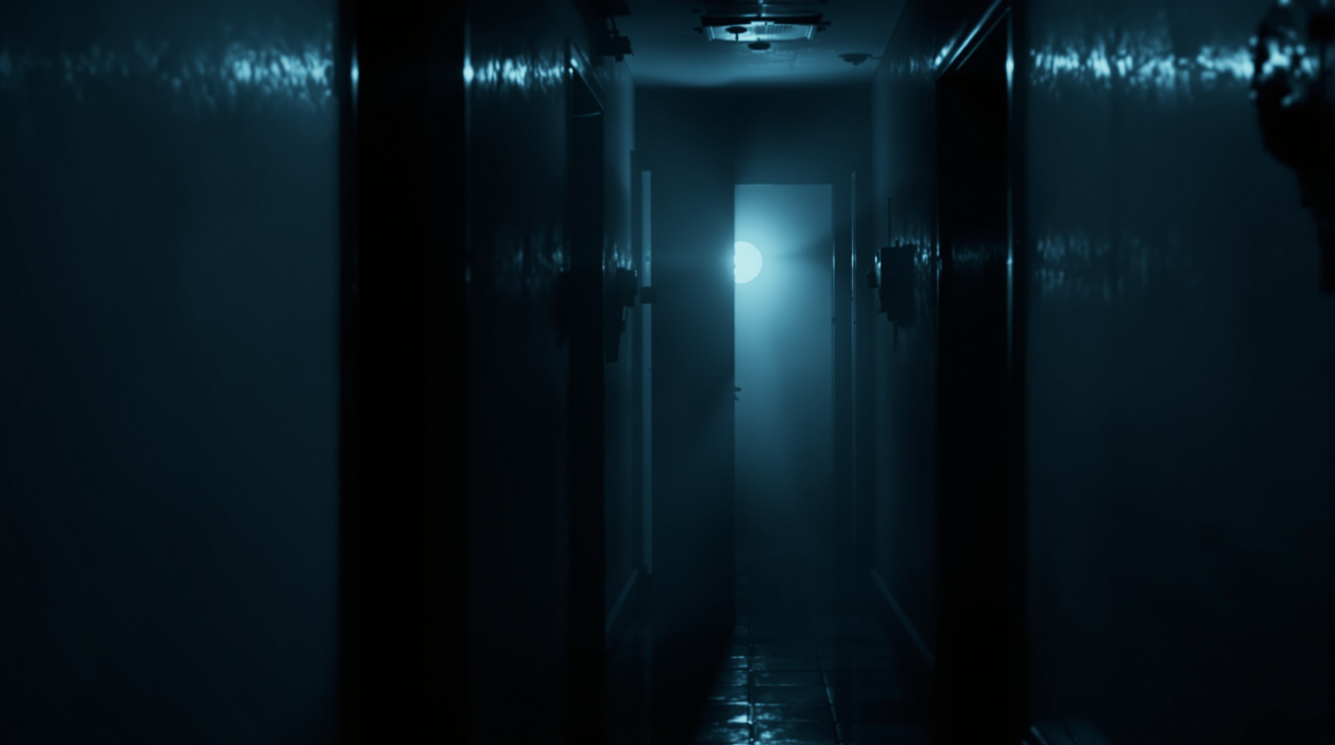A dim hallway with cold moonlight and a partially open door